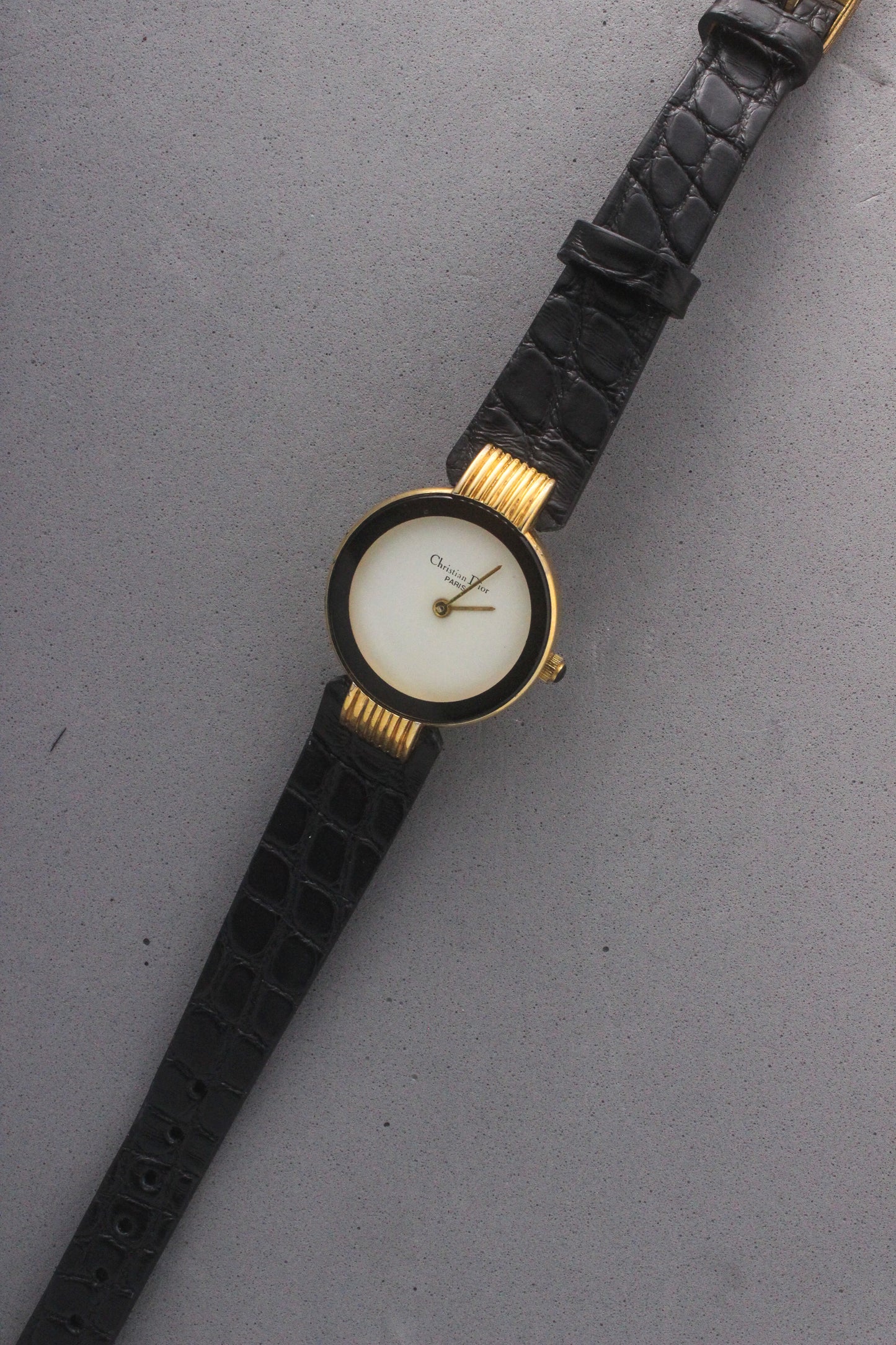 Elegant Christian Dior Paris vintage watch featuring a minimalist gold-plated round case, black enamel bezel, sleek black alligator leather strap, and classic white dial with gold-tone hands. A luxurious and timeless accessory for discerning collectors and fashion enthusiasts. ref. 900-11