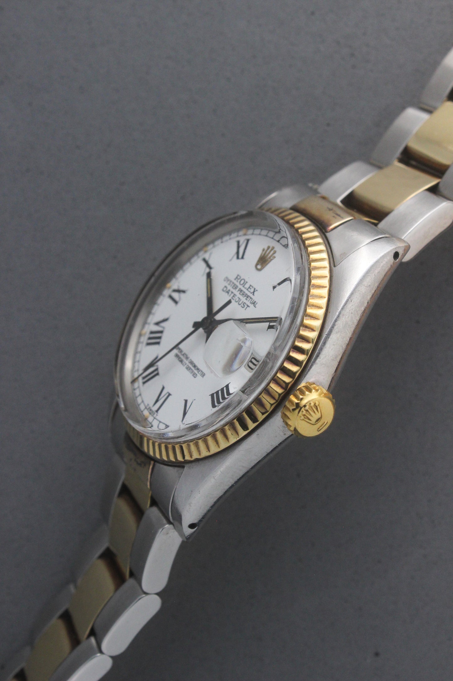 Rolex Datejust reference number 16013, featuring a two-tone stainless steel and yellow gold Jubilee bracelet, a fluted yellow gold bezel, and a classic white dial with black Roman numeral hour markers. The watch includes a date window at 3 o’clock, magnified by a Cyclops lens, and the ‘Rolex Oyster Perpetual Datejust’ text on the dial, showcasing its timeless and elegant design.