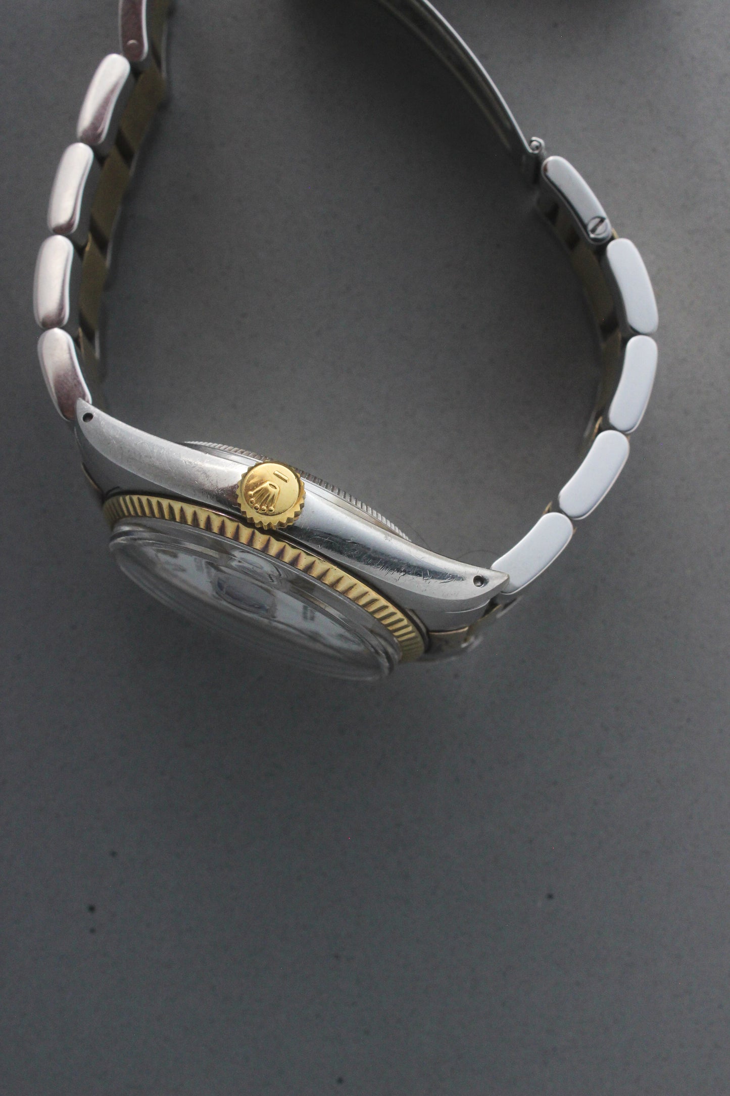 Side profile of the Rolex Datejust reference number 16013, showcasing the iconic yellow gold screw-down crown embossed with the Rolex coronet. The image highlights the fluted yellow gold bezel and the smooth curves of the stainless steel case, reflecting the watch’s exceptional craftsmanship and timeless elegance.