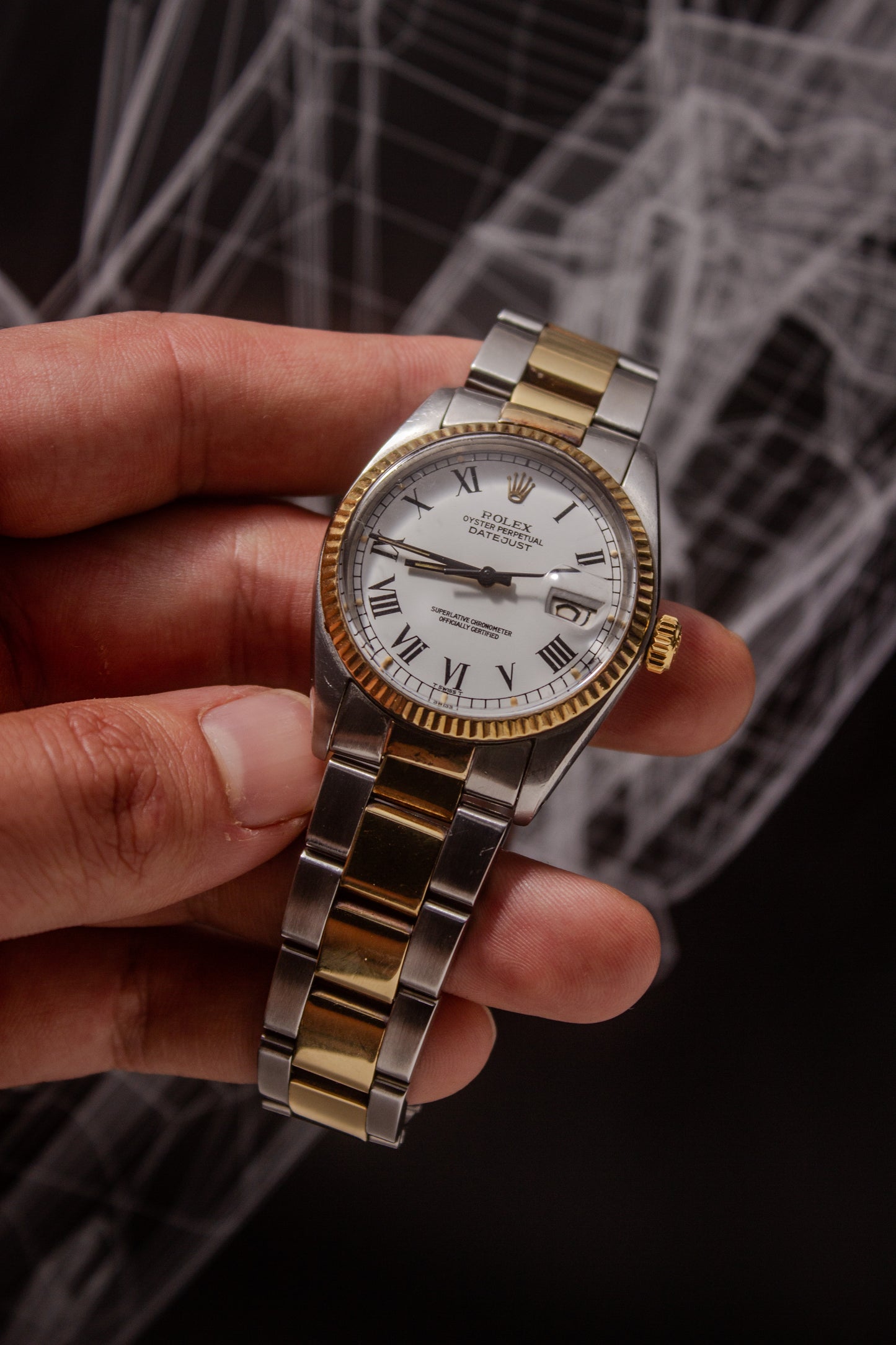 Rolex Datejust reference number 16013, featuring a two-tone stainless steel and yellow gold Jubilee bracelet, a fluted yellow gold bezel, and a classic white dial with black Roman numeral hour markers. The watch includes a date window at 3 o’clock, magnified by a Cyclops lens, and the ‘Rolex Oyster Perpetual Datejust’ text on the dial, showcasing its timeless and elegant design.
