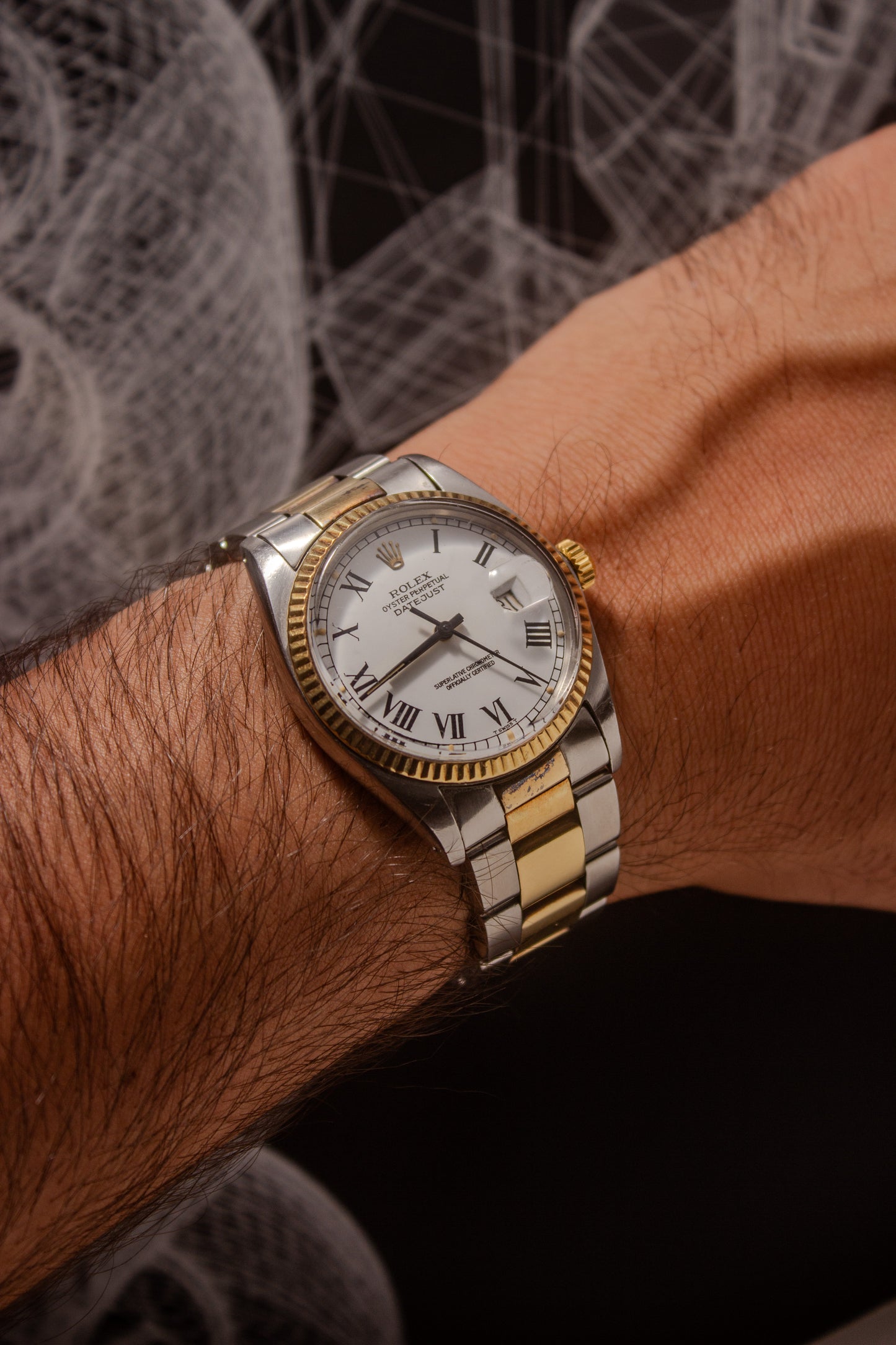 Rolex Datejust reference number 16013, featuring a two-tone stainless steel and yellow gold Jubilee bracelet, a fluted yellow gold bezel, and a classic white dial with black Roman numeral hour markers. The watch includes a date window at 3 o’clock, magnified by a Cyclops lens, and the ‘Rolex Oyster Perpetual Datejust’ text on the dial, showcasing its timeless and elegant design.