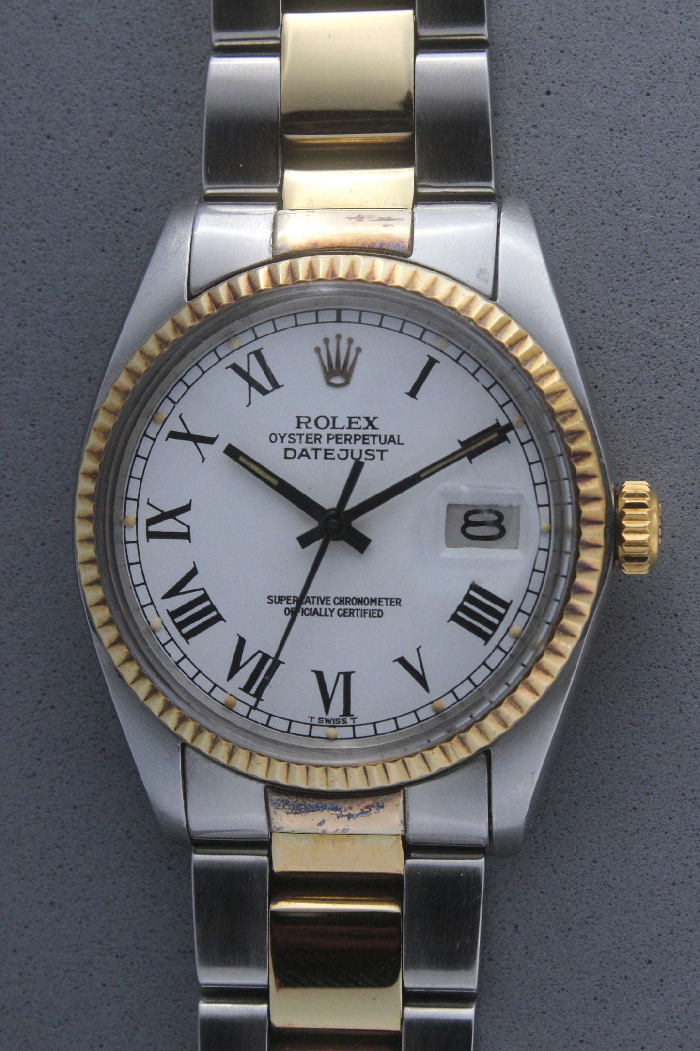 Rolex Datejust reference number 16013, featuring a two-tone stainless steel and yellow gold Jubilee bracelet, a fluted yellow gold bezel, and a classic white dial with black Roman numeral hour markers. The watch includes a date window at 3 o’clock, magnified by a Cyclops lens, and the ‘Rolex Oyster Perpetual Datejust’ text on the dial, showcasing its timeless and elegant design.