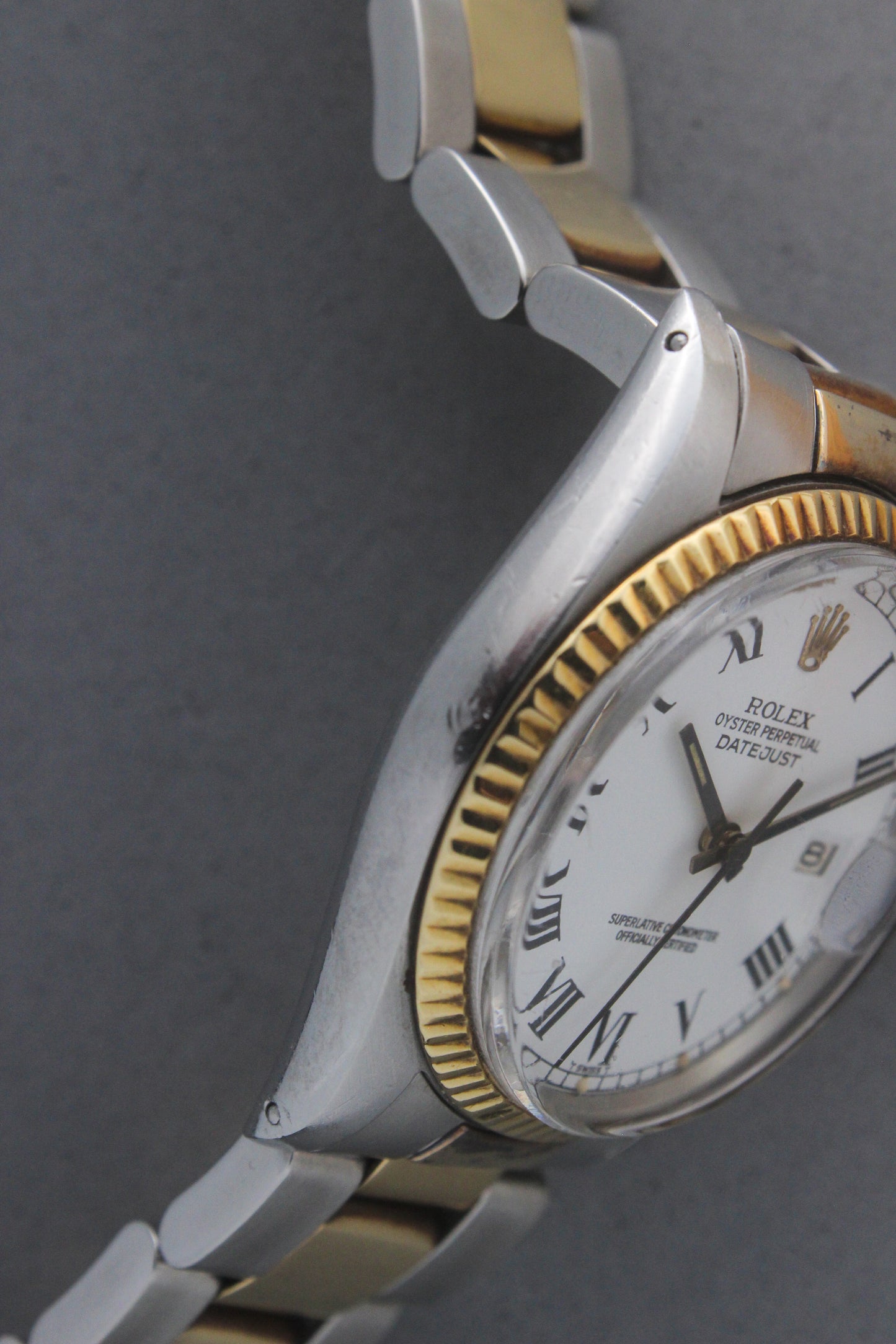 Rolex Datejust reference number 16013, featuring a two-tone stainless steel and yellow gold Jubilee bracelet, a fluted yellow gold bezel, and a classic white dial with black Roman numeral hour markers. The watch includes a date window at 3 o’clock, magnified by a Cyclops lens, and the ‘Rolex Oyster Perpetual Datejust’ text on the dial, showcasing its timeless and elegant design.