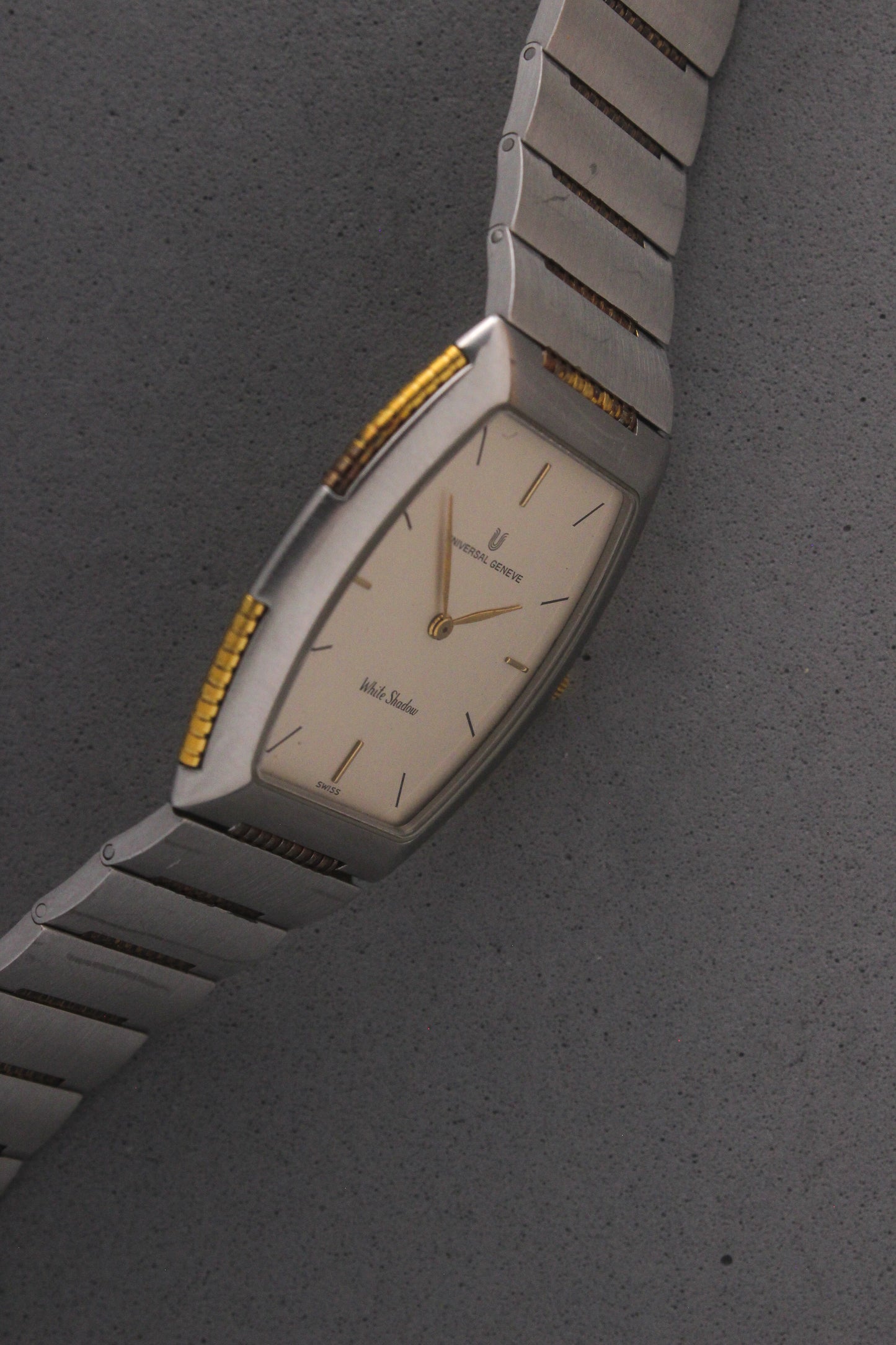 Front View of Universal Genève White Shadow Ref. 617-020
A close-up of the Universal Genève White Shadow Ref. 617-020, featuring a sleek tonneau-shaped stainless steel case with gold accents, a clean white dial, and minimalist stick hands and indices. Paired with an integrated stainless steel bracelet for timeless elegance.