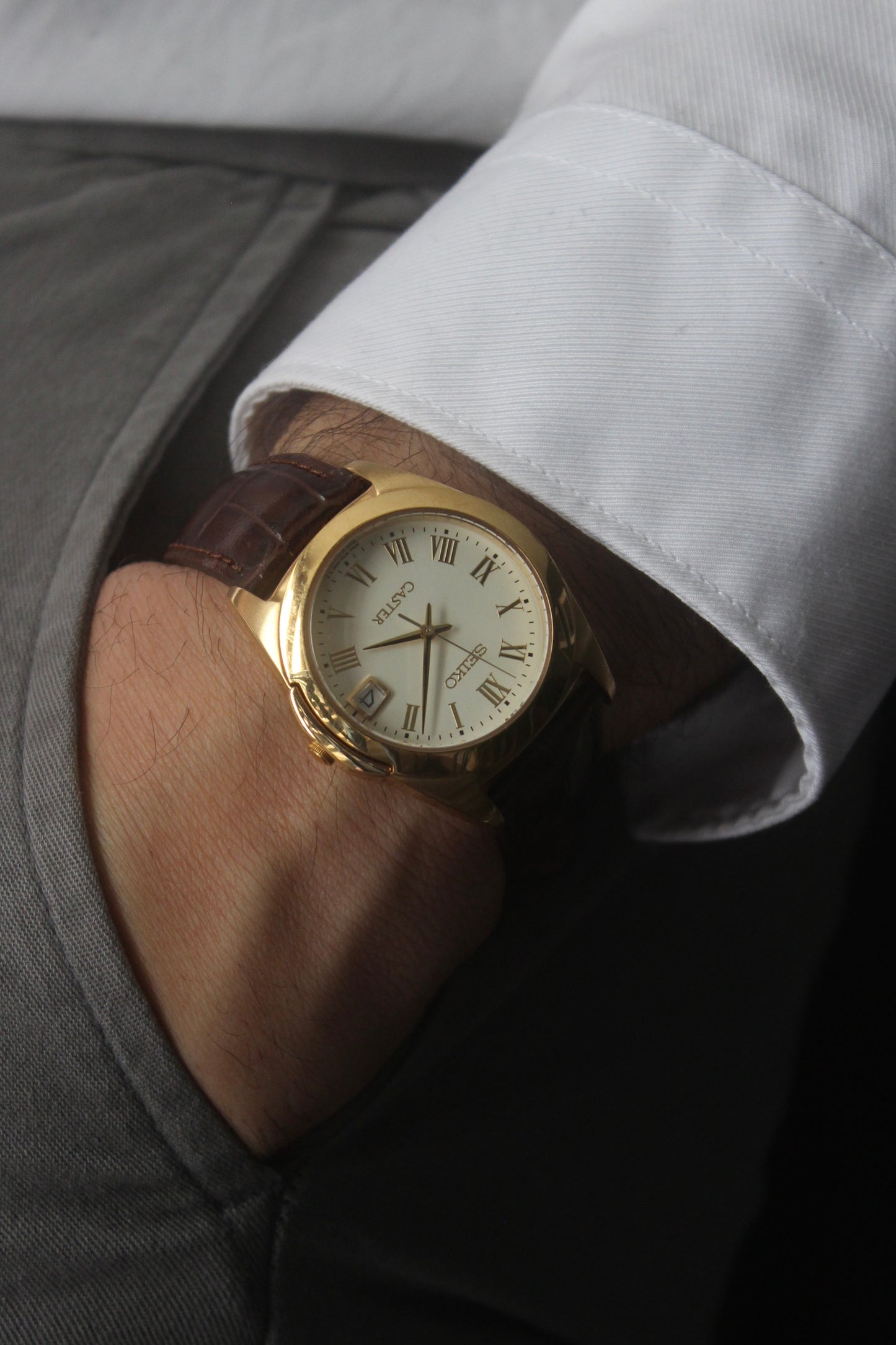 A detailed front view of the Seiko Caster
8F32-0140 watch featuring a gold-tone case, Roman numeral markers, and a date window at 3 o'clock. The cream-colored dial is complemented by classic black hands, encapsulating an elegant vintage aesthetic.
Paired with a genuine brown leather strap.