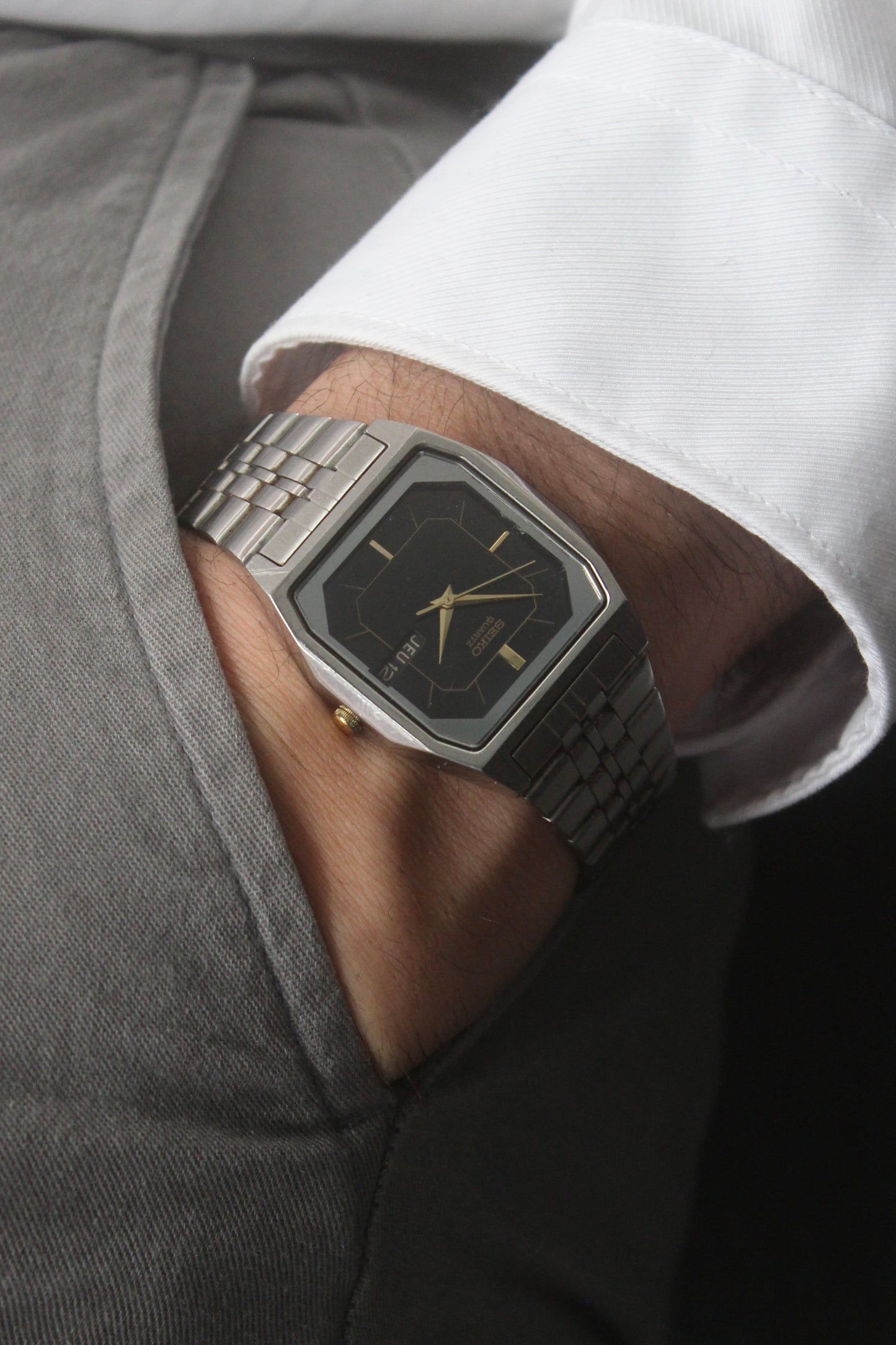 A close-up of the Seiko Dolce Quartz 7N43-5011, featuring a rectangular stainless steel case, black dial with gold accents, and a day-date window at 3 o'clock. The watch is paired with a stainless steel bracelet, exuding a timeless and versatile design.