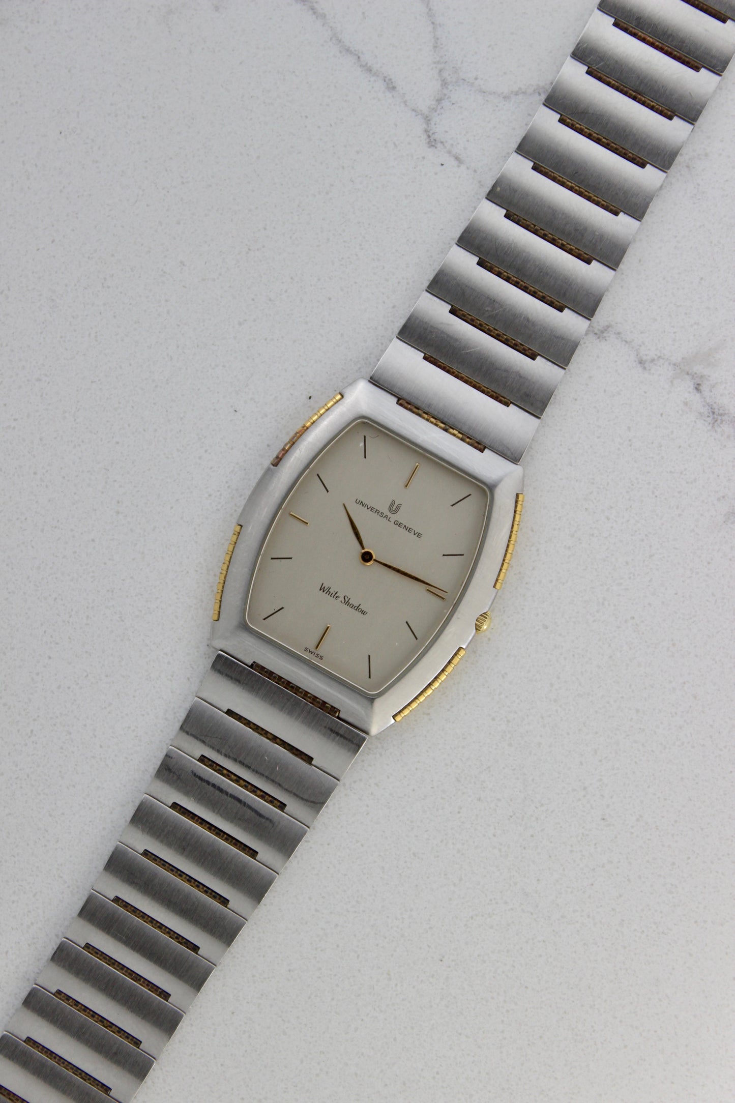 Front View of Universal Genève White Shadow Ref. 617-020
A close-up of the Universal Genève White Shadow Ref. 617-020, featuring a sleek tonneau-shaped stainless steel case with gold accents, a clean white dial, and minimalist stick hands and indices. Paired with an integrated stainless steel bracelet for timeless elegance.