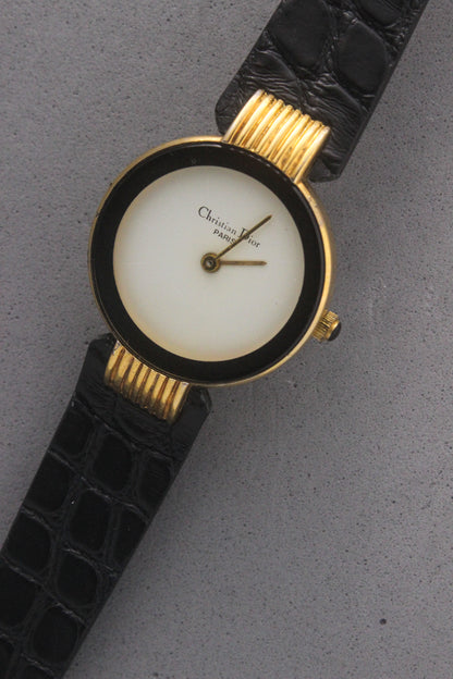 Elegant Christian Dior Paris vintage watch featuring a minimalist gold-plated round case, black enamel bezel, sleek black alligator leather strap, and classic white dial with gold-tone hands. A luxurious and timeless accessory for discerning collectors and fashion enthusiasts. ref. 900-11
