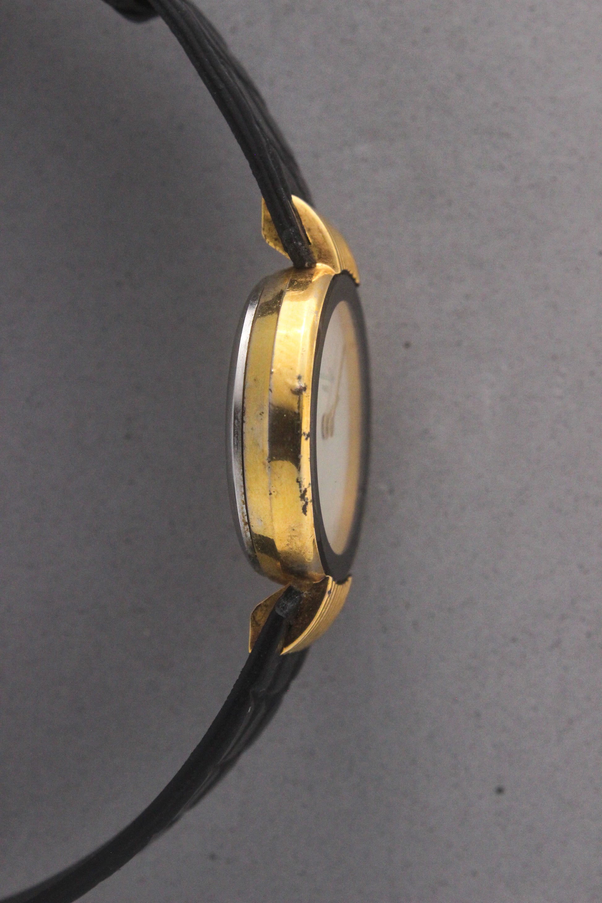 Elegant Christian Dior Paris vintage watch featuring a minimalist gold-plated round case, black enamel bezel, sleek black alligator leather strap, and classic white dial with gold-tone hands. A luxurious and timeless accessory for discerning collectors and fashion enthusiasts. ref. 900-11