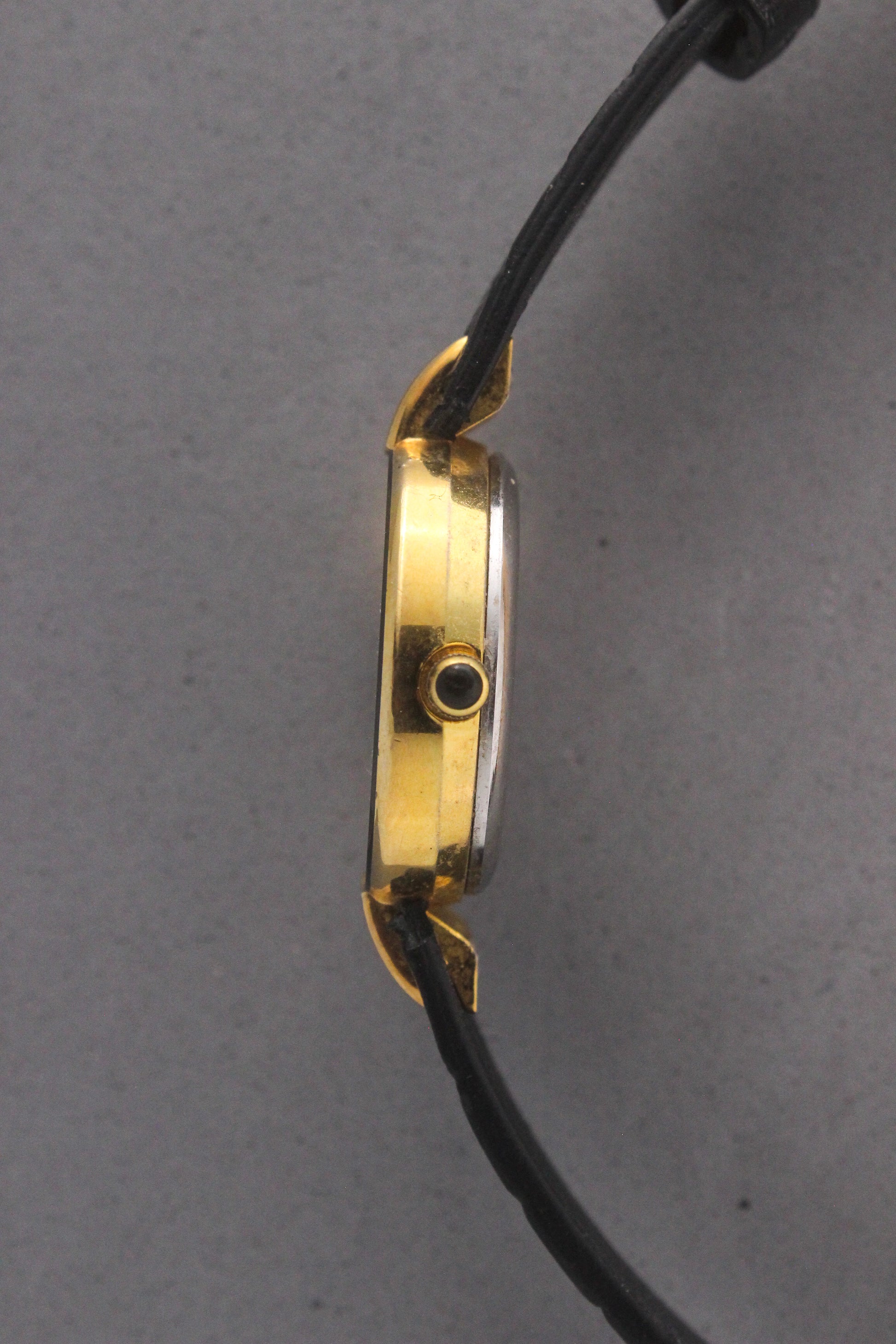 Elegant Christian Dior Paris vintage watch featuring a minimalist gold-plated round case, black enamel bezel, sleek black alligator leather strap, and classic white dial with gold-tone hands. A luxurious and timeless accessory for discerning collectors and fashion enthusiasts. ref. 900-11