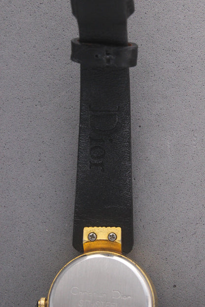 Back view of a Christian Dior Paris vintage watch, ref. 900-11, showcasing a stainless steel case back with engravings and gold-tone accents. Attached to a sleek black leather strap, this timepiece embodies luxury and sophistication, making it a must-have for vintage watch collectors.