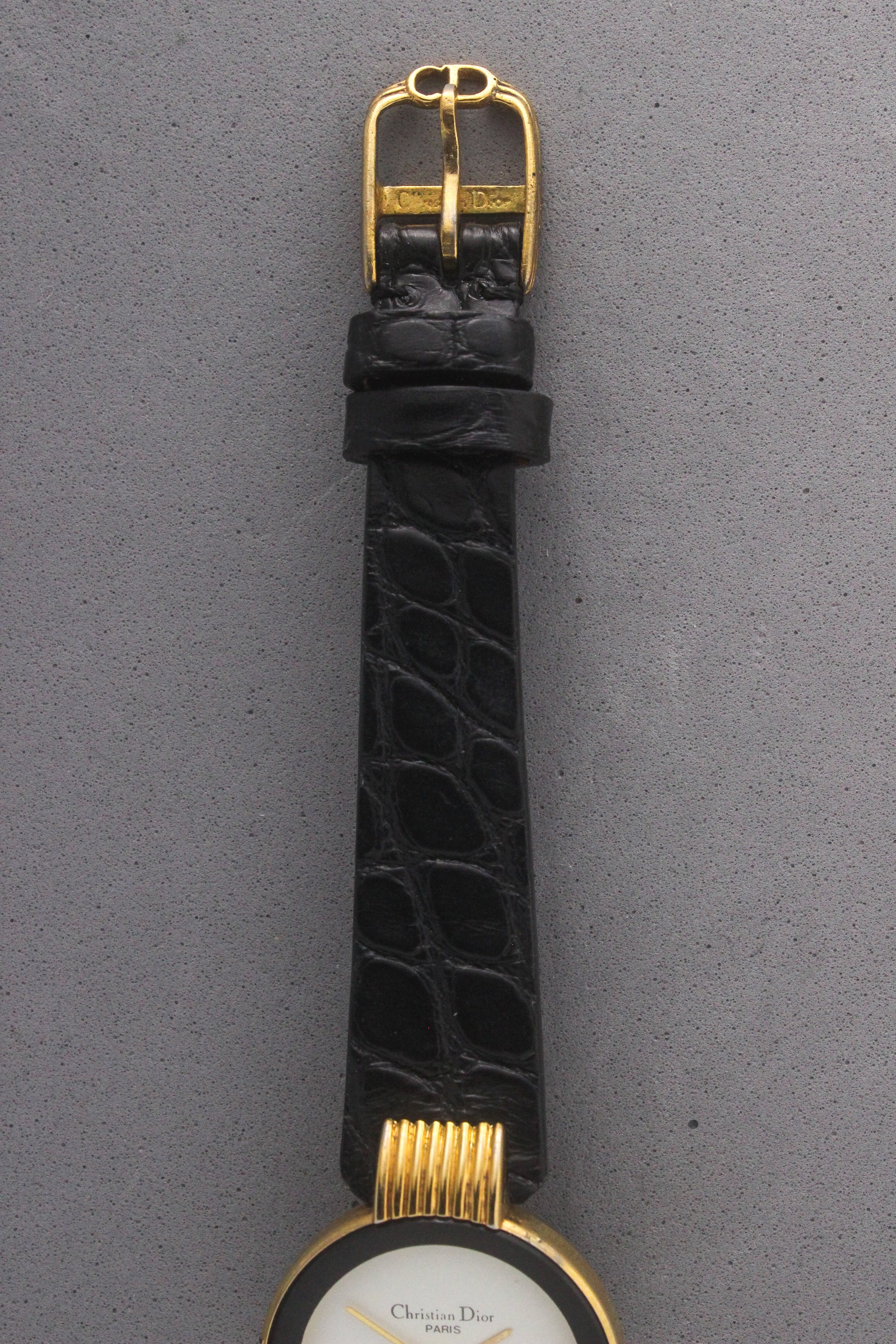 Close-up of the Christian Dior Paris vintage watch’s black alligator leather strap with a gold-tone buckle engraved with the ‘Christian Dior’ logo. A luxurious finishing touch that enhances the elegance and sophistication of this timeless timepiece, ref. 900-11.