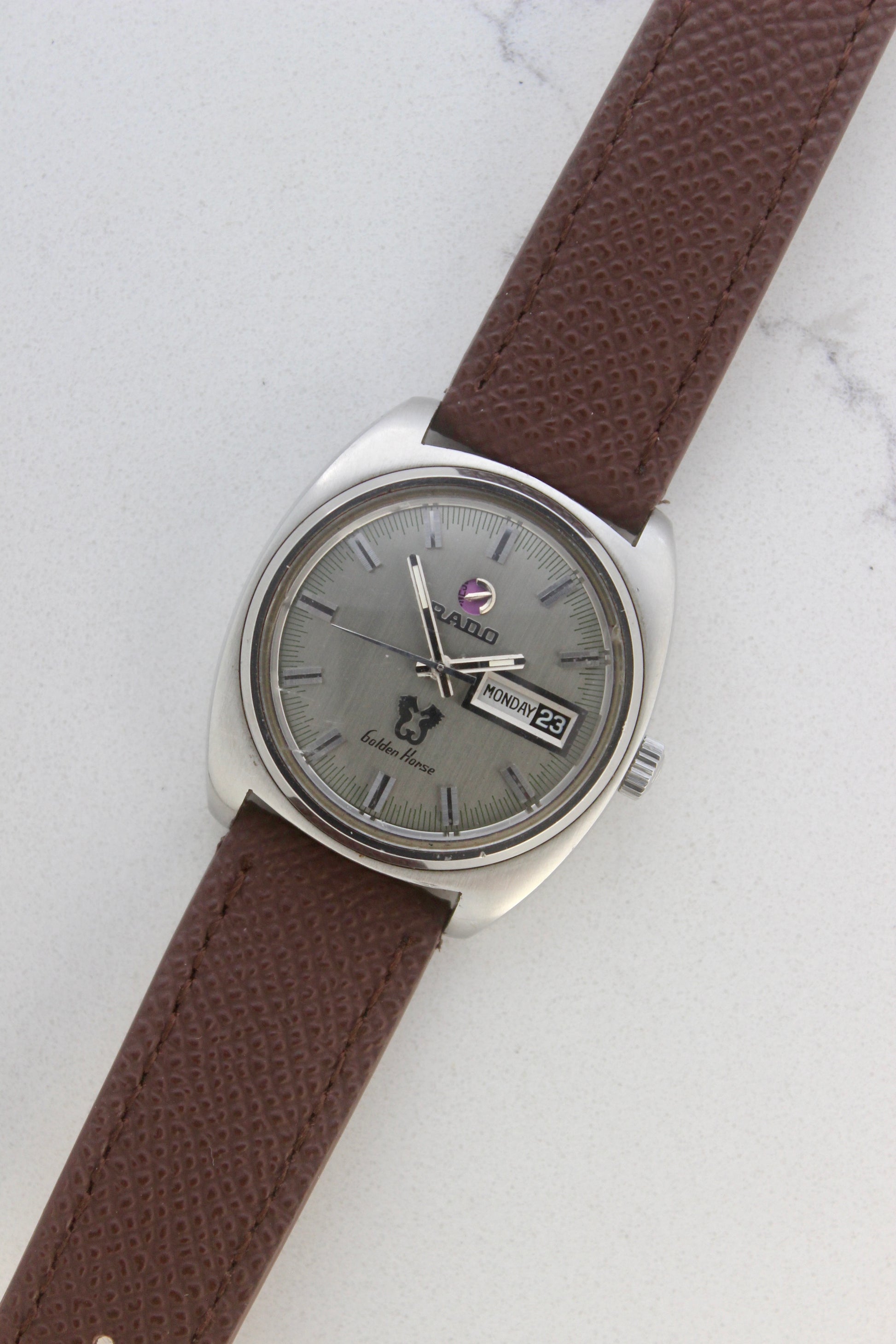 Vintage Rado Golden Horse watch, reference number 11816, featuring brown strap, silver-tone dial with baton hour markers, day-date display at 3 o’clock, and the signature Golden Horse logo. A timeless and elegant collector’s timepiece from Rado.