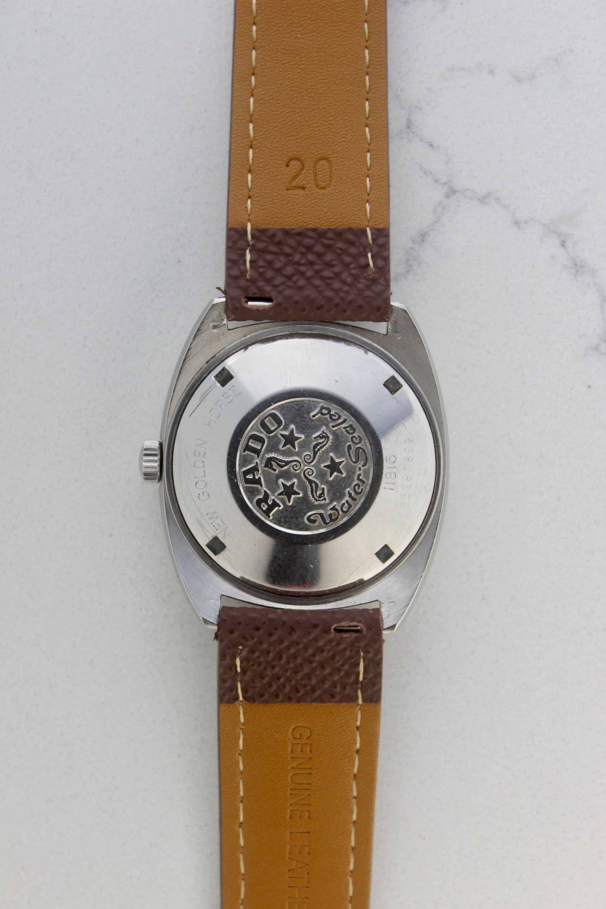 Case back of the Rado Golden Horse watch, reference number 11816, showcasing the engraved emblem featuring seahorses, stars, and the ‘Rado’ branding. Surrounding the emblem are the inscriptions ‘New Golden Horse’ and ‘Water Sealed,’ highlighting the timepiece’s durability and classic design.