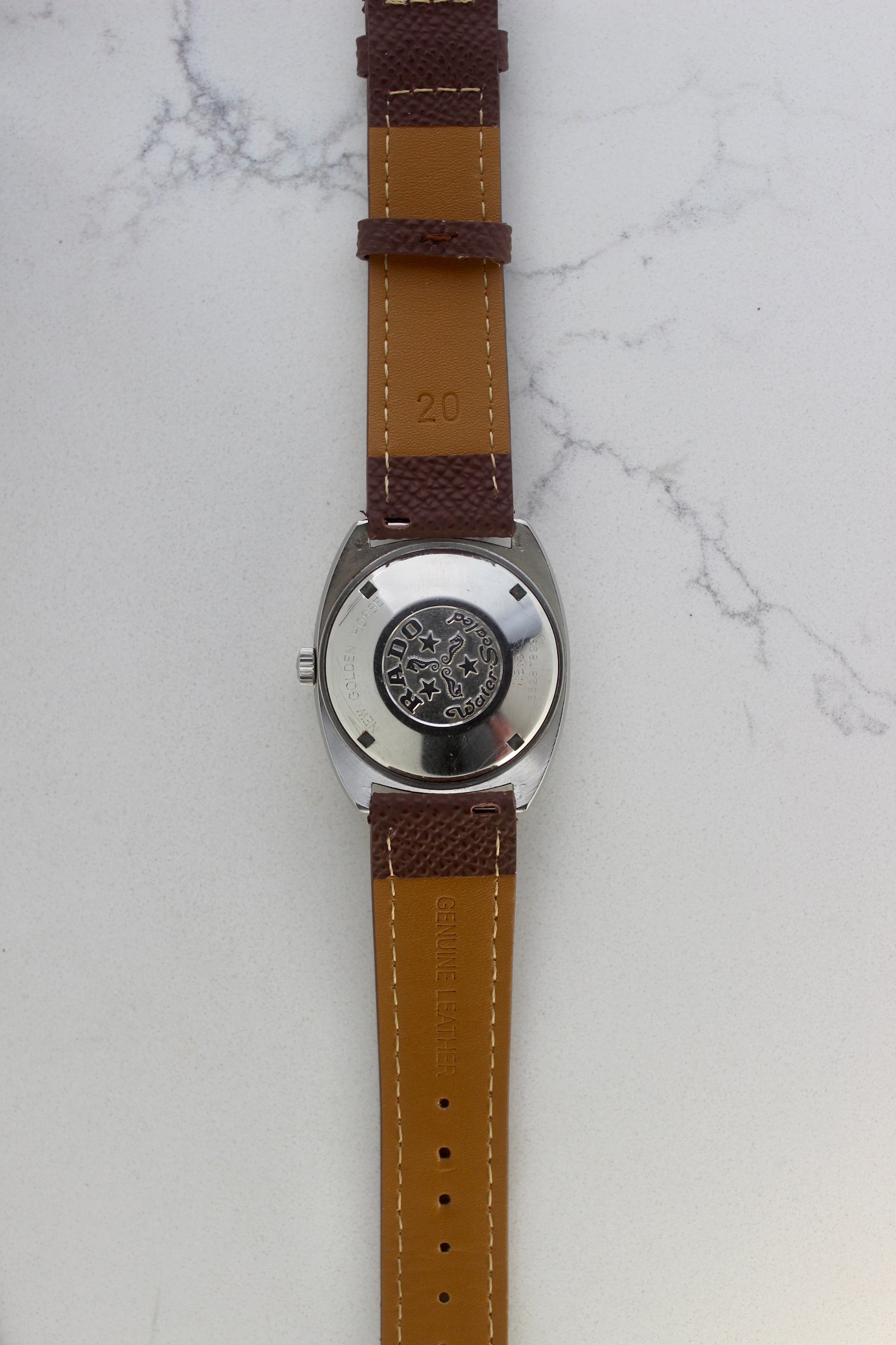 Case back of the Rado Golden Horse watch, reference number 11816, showcasing the engraved emblem featuring seahorses, stars, and the ‘Rado’ branding. Surrounding the emblem are the inscriptions ‘New Golden Horse’ and ‘Water Sealed,’ highlighting the timepiece’s durability and classic design.