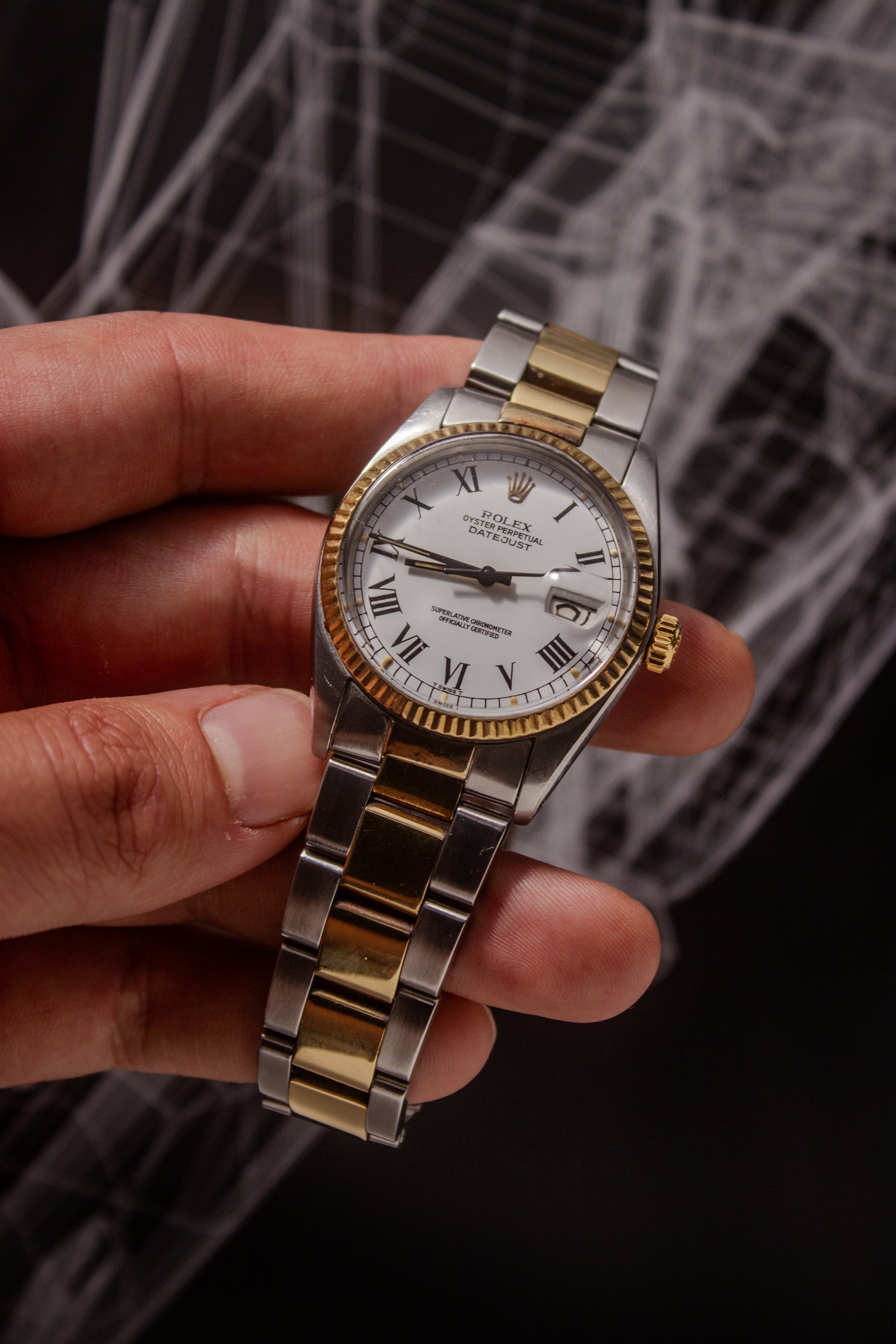 Rolex Datejust reference number 16013, featuring a two-tone stainless steel and yellow gold Jubilee bracelet, a fluted yellow gold bezel, and a classic white dial with black Roman numeral hour markers. The watch includes a date window at 3 o’clock, magnified by a Cyclops lens, and the ‘Rolex Oyster Perpetual Datejust’ text on the dial, showcasing its timeless and elegant design.