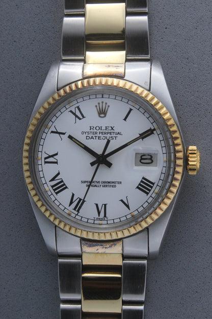 Rolex Datejust reference number 16013, featuring a two-tone stainless steel and yellow gold Jubilee bracelet, a fluted yellow gold bezel, and a classic white dial with black Roman numeral hour markers. The watch includes a date window at 3 o’clock, magnified by a Cyclops lens, and the ‘Rolex Oyster Perpetual Datejust’ text on the dial, showcasing its timeless and elegant design.