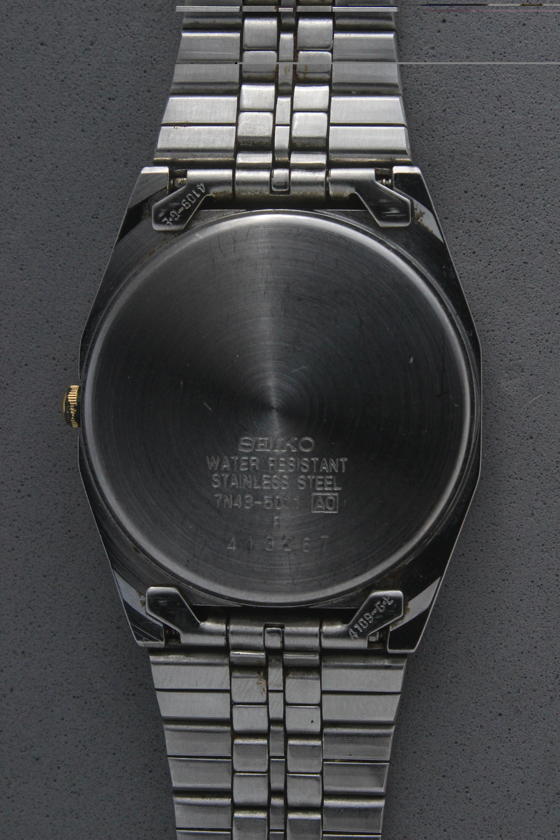 A close-up of the stainless steel case back for the Seiko Quartz 7N43-5011, engraved with model details including "7N43-5011,"
"Water Resistant," and "Made in Japan." The brushed finish highlights the craftsmanship and quality.
