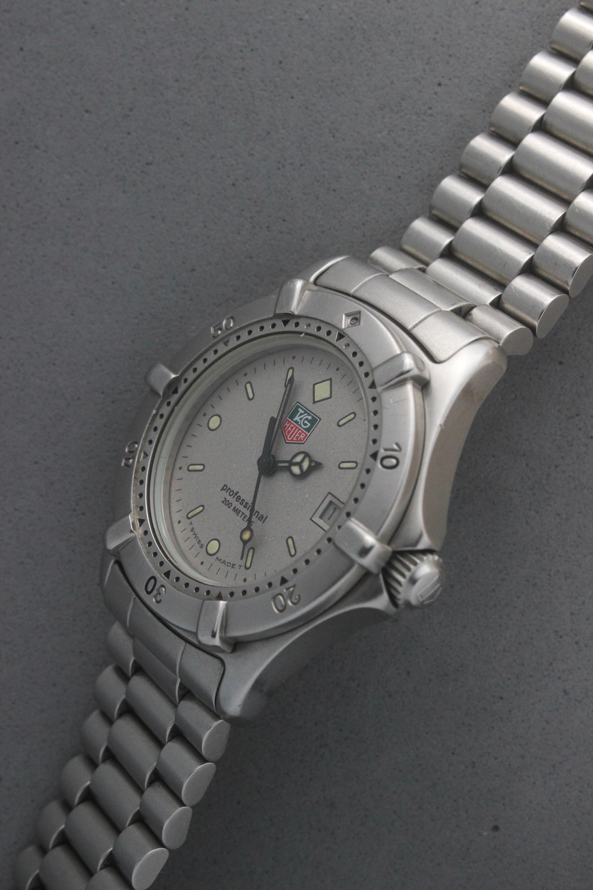 Close-up of the TAG Heuer Professional Ref.
962.213R case back showcasing engravings including "962.213R," "Water Resistant 200m
Tested," and "Swiss Made." The TAG Heuer logo and brushed stainless steel highlight the quality craftsmanship.