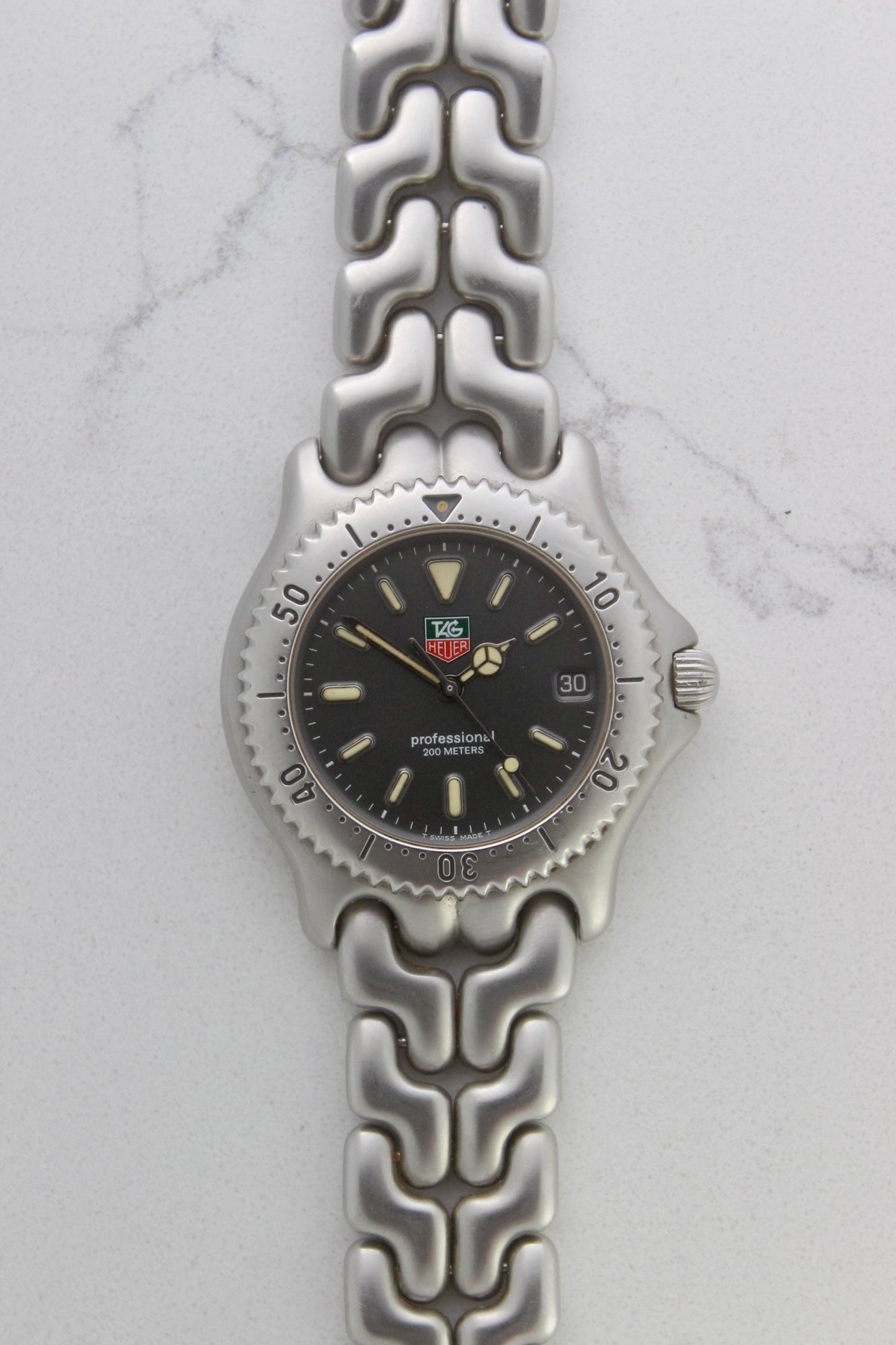 Tag Heuer Professional S/EL Ref. S99.206 stainless steel quartz dive watch with a 39mm case, volcanic grey dial, luminous markers, and rotating diver bezel. Features an original 7" bracelet, date window at 3 o’clock, and durable sapphire crystal. A rare vintage timepiece in excellent condition, perfect for collectors and enthusiasts.