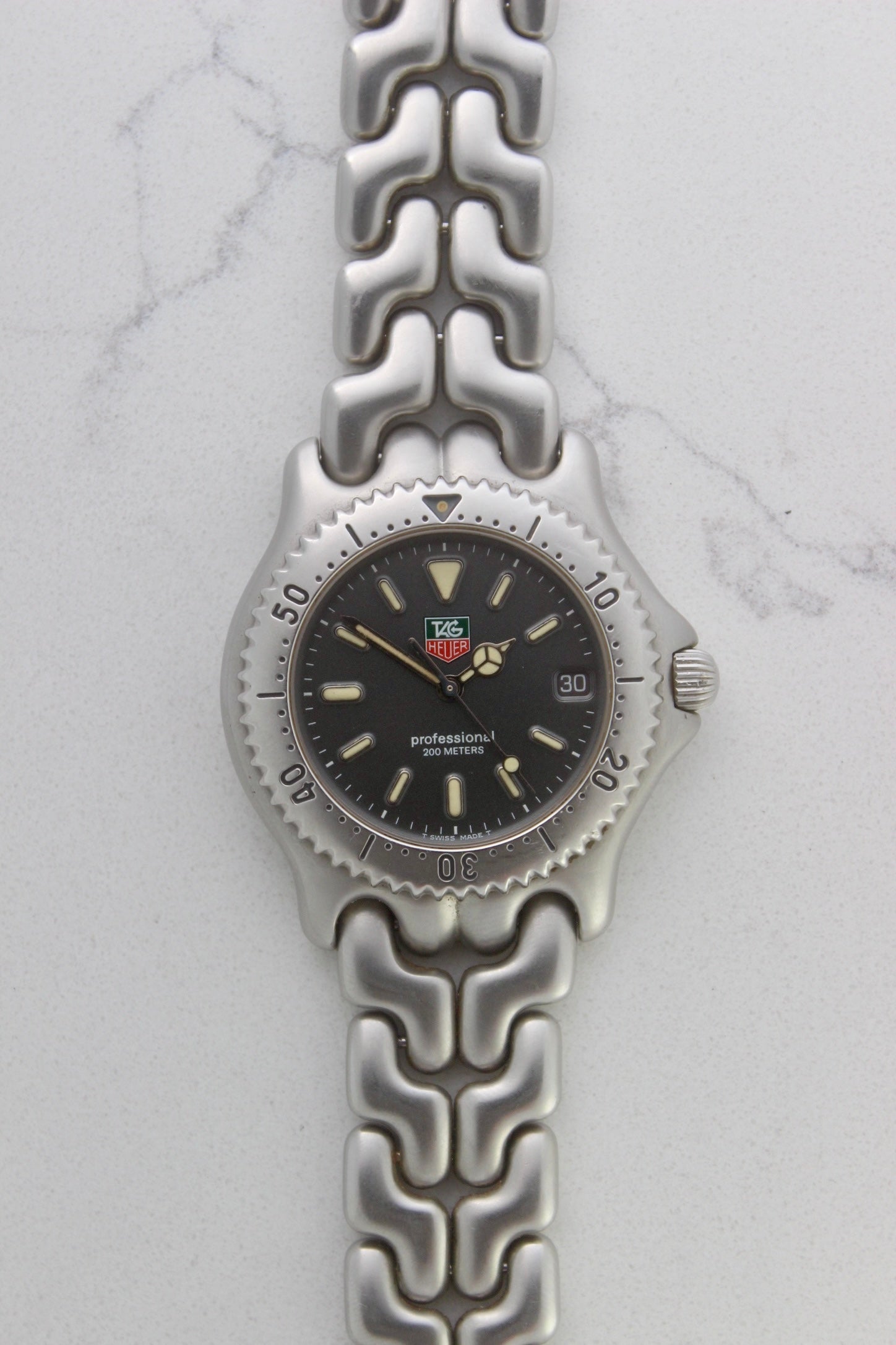 Tag Heuer Professional S/EL Ref. S99.206 stainless steel quartz dive watch with a 39mm case, volcanic grey dial, luminous markers, and rotating diver bezel. Features an original 7" bracelet, date window at 3 o’clock, and durable sapphire crystal. A rare vintage timepiece in excellent condition, perfect for collectors and enthusiasts.