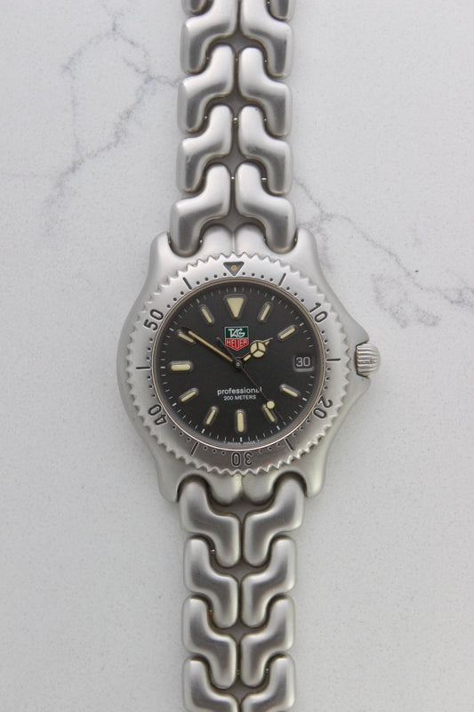 Tag Heuer Professional S/EL Ref. S99.206 stainless steel quartz dive watch with a 39mm case, volcanic grey dial, luminous markers, and rotating diver bezel. Features an original 7" bracelet, date window at 3 o’clock, and durable sapphire crystal. A rare vintage timepiece in excellent condition, perfect for collectors and enthusiasts.