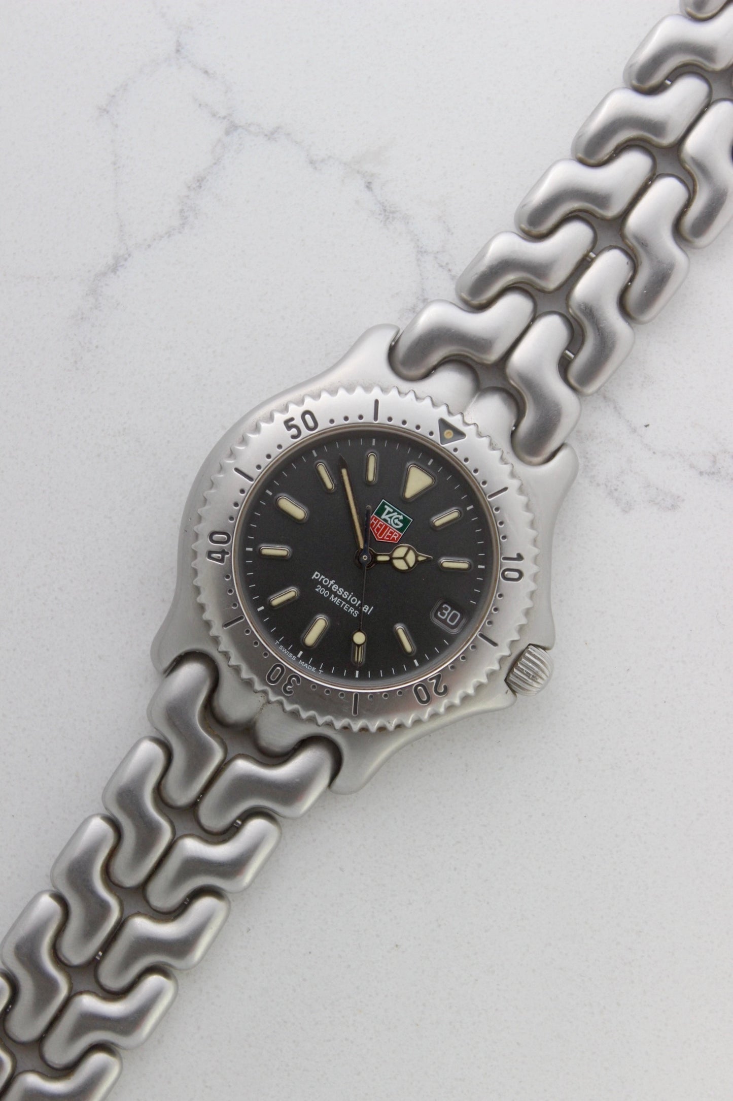 Tag Heuer Professional S/EL Ref. S99.206 stainless steel quartz dive watch with a 39mm case, volcanic grey dial, luminous markers, and rotating diver bezel. Features an original 7" bracelet, date window at 3 o’clock, and durable sapphire crystal. A rare vintage timepiece in excellent condition, perfect for collectors and enthusiasts.