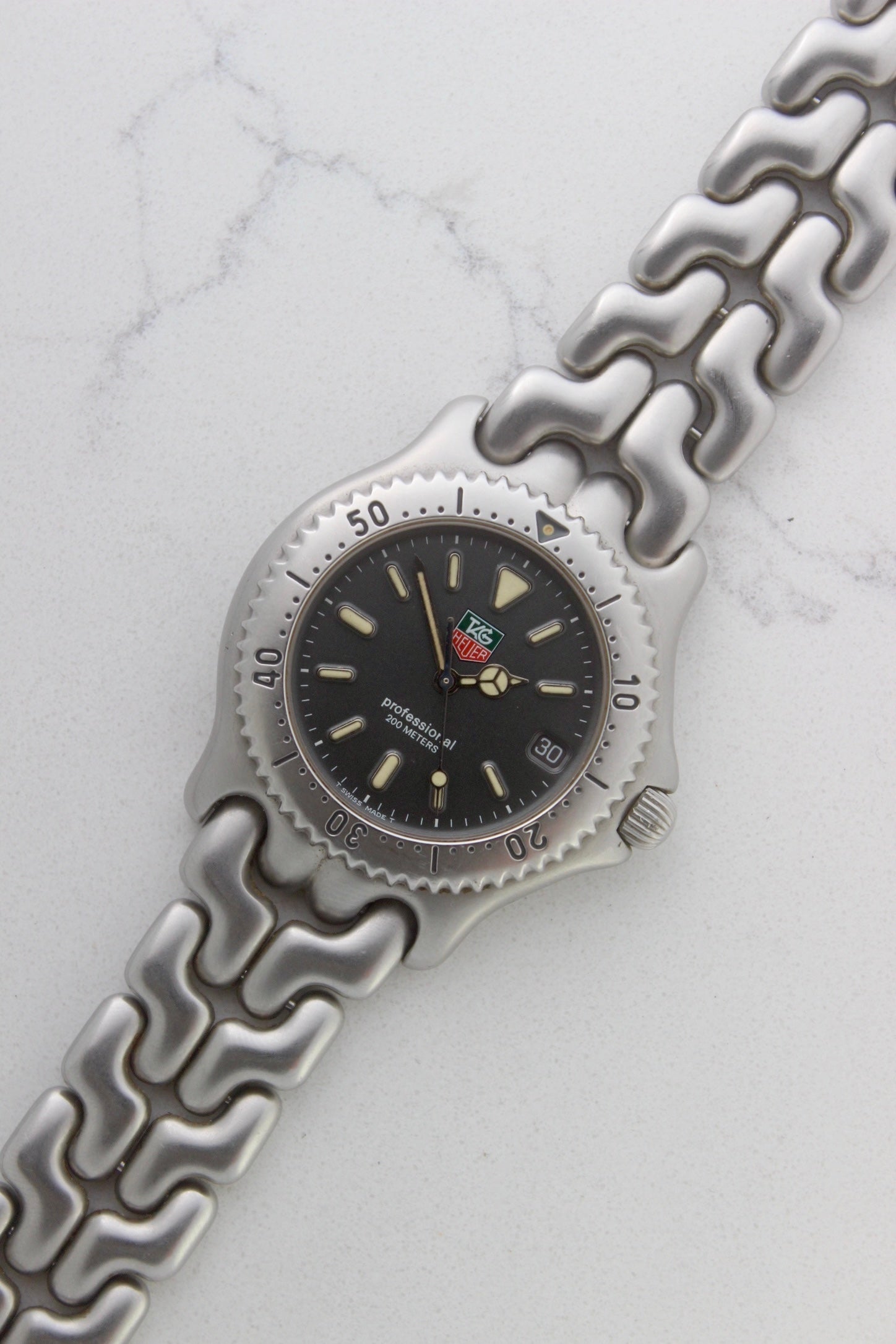 Tag Heuer Professional S/EL Ref. S99.206 stainless steel quartz dive watch with a 39mm case, volcanic grey dial, luminous markers, and rotating diver bezel. Features an original 7" bracelet, date window at 3 o’clock, and durable sapphire crystal. A rare vintage timepiece in excellent condition, perfect for collectors and enthusiasts.