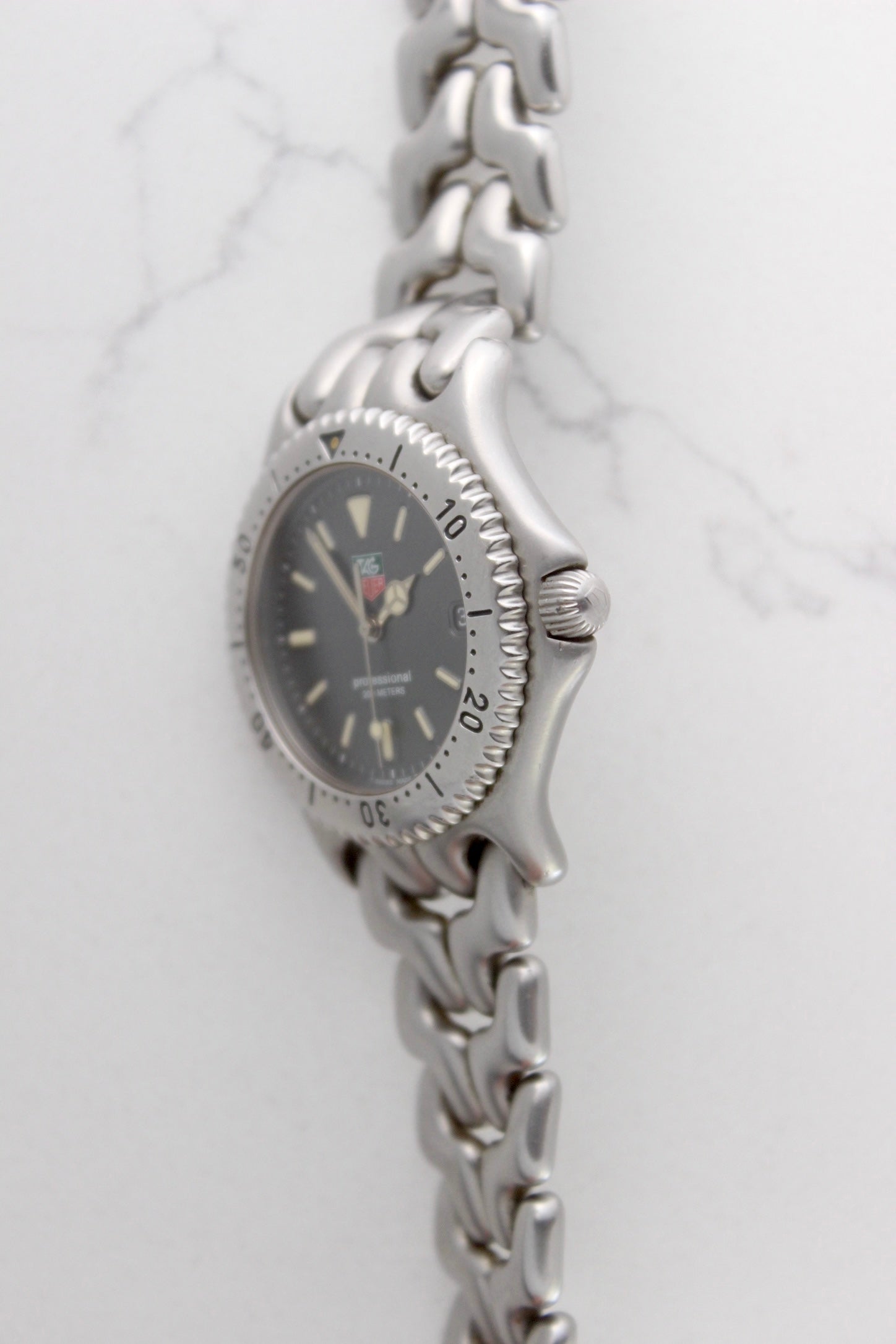 Tag Heuer Professional S/EL Ref. S99.206 stainless steel quartz dive watch with a 39mm case, volcanic grey dial, luminous markers, and rotating diver bezel. Features an original 7" bracelet, date window at 3 o’clock, and durable sapphire crystal. A rare vintage timepiece in excellent condition, perfect for collectors and enthusiasts.