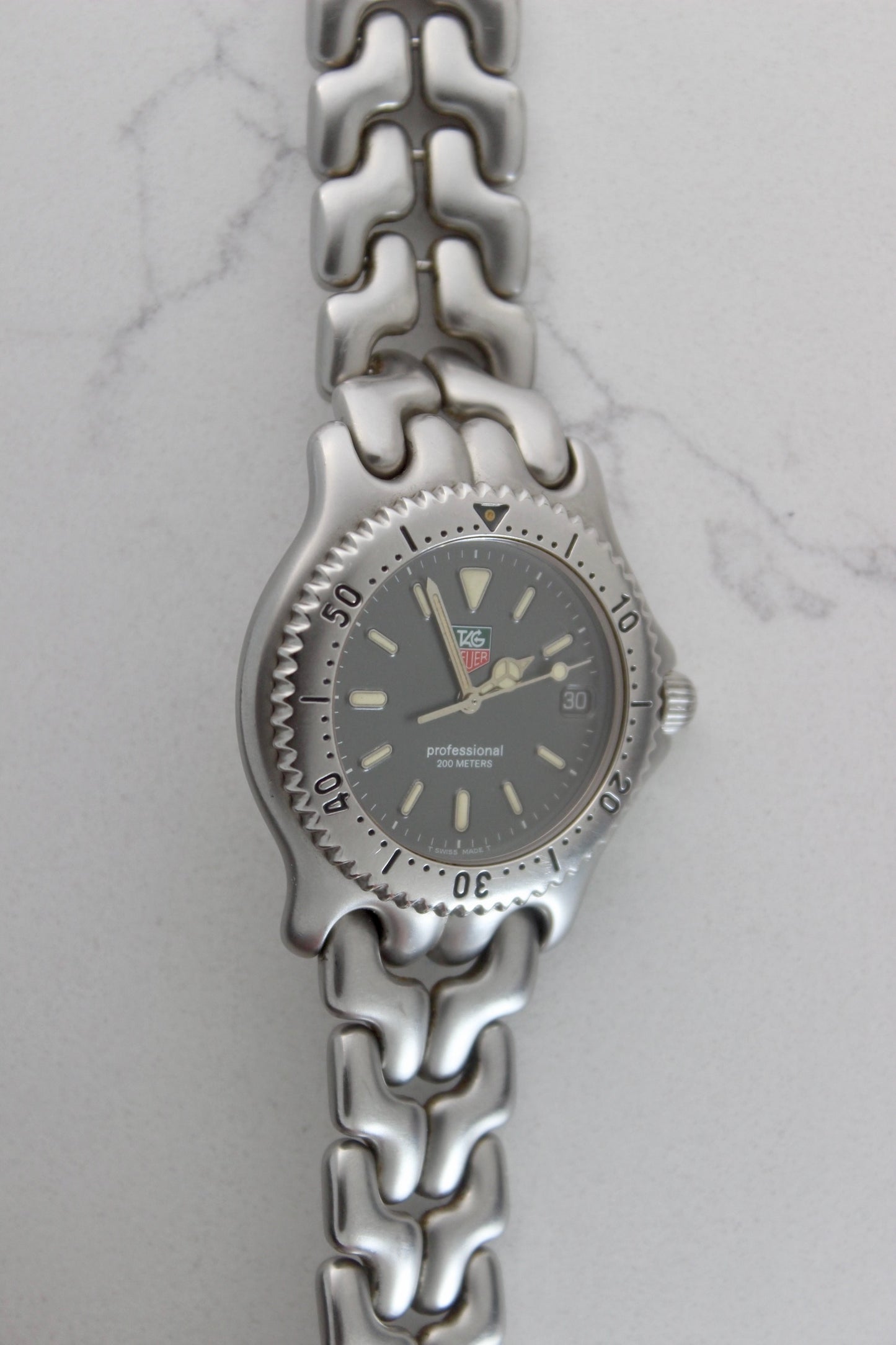 Tag Heuer Professional S/EL Ref. S99.206 stainless steel quartz dive watch with a 39mm case, volcanic grey dial, luminous markers, and rotating diver bezel. Features an original 7" bracelet, date window at 3 o’clock, and durable sapphire crystal. A rare vintage timepiece in excellent condition, perfect for collectors and enthusiasts.