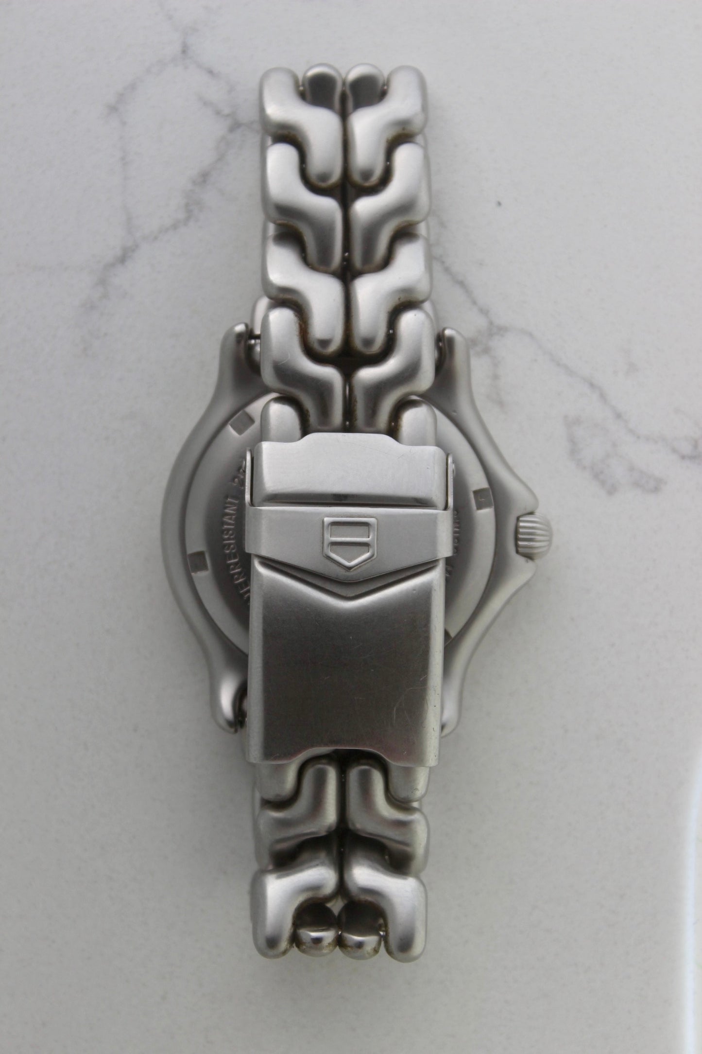 Tag Heuer S/EL Professional watch clasp, featuring the iconic stainless steel bracelet with a secure fold-over clasp engraved with the Tag Heuer shield logo. A durable and stylish vintage timepiece component.