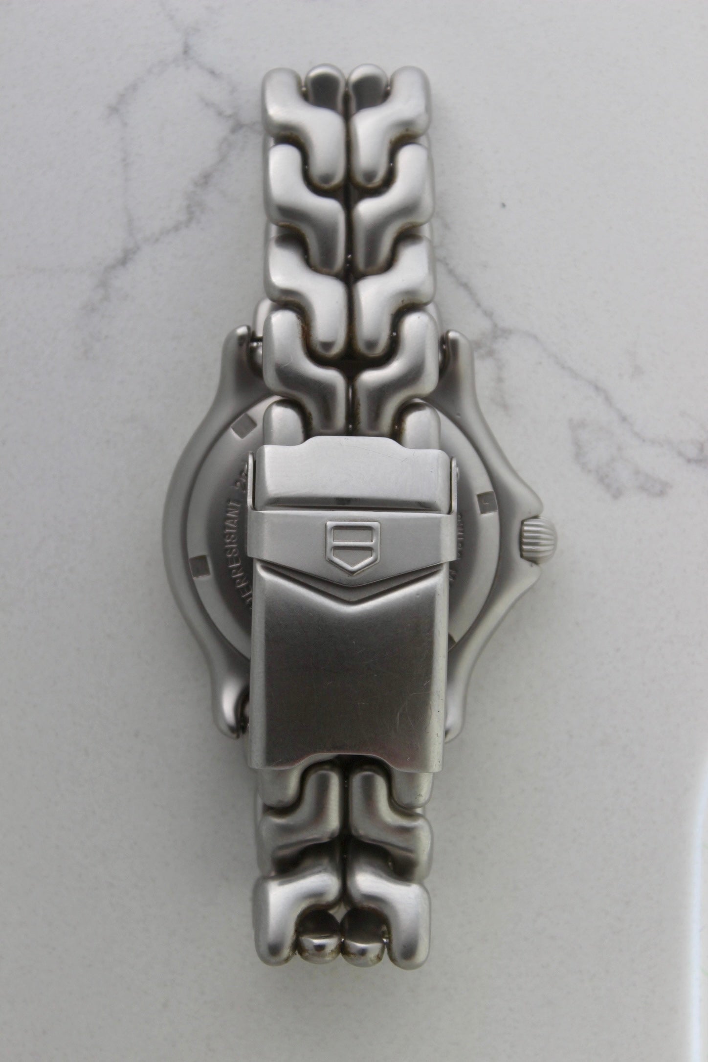 Tag Heuer S/EL Professional watch clasp, featuring the iconic stainless steel bracelet with a secure fold-over clasp engraved with the Tag Heuer shield logo. A durable and stylish vintage timepiece component.