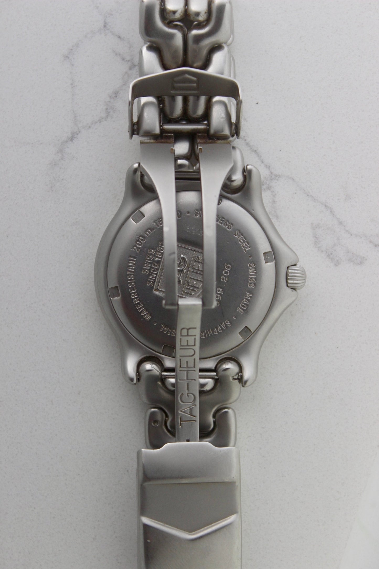 Tag Heuer S/EL Professional watch clasp, featuring the iconic stainless steel bracelet with a secure fold-over clasp engraved with the Tag Heuer shield logo. A durable and stylish vintage timepiece component.