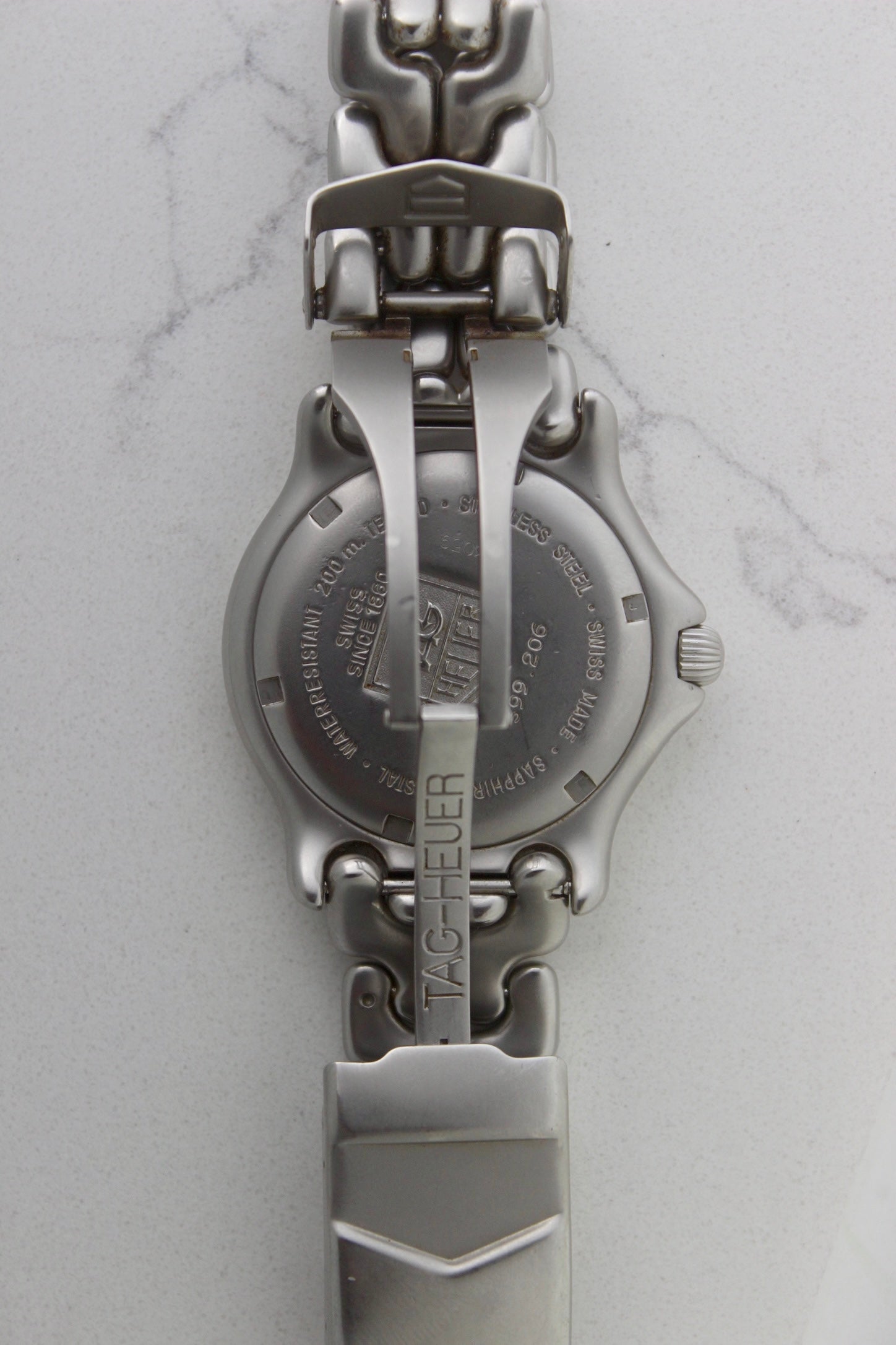Tag Heuer S/EL Professional watch clasp, featuring the iconic stainless steel bracelet with a secure fold-over clasp engraved with the Tag Heuer shield logo. A durable and stylish vintage timepiece component.