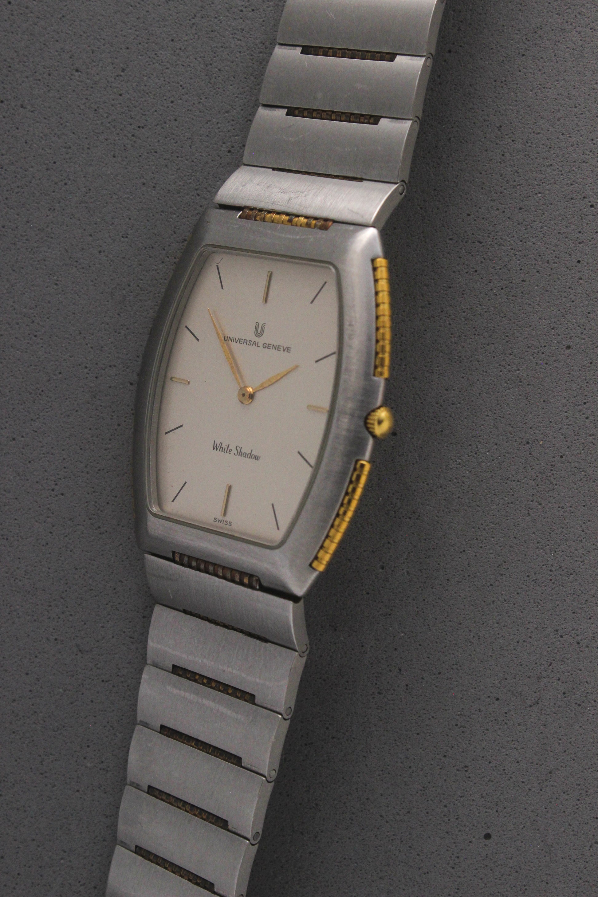 Front View of Universal Genève White Shadow Ref. 617-020
A close-up of the Universal Genève White Shadow Ref. 617-020, featuring a sleek tonneau-shaped stainless steel case with gold accents, a clean white dial, and minimalist stick hands and indices. Paired with an integrated stainless steel bracelet for timeless elegance.