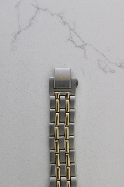 vintage Seiko Dolce AGS wristwatch with a two-tone stainless steel and gold-plated bracelet, set against a light-colored marble background. The watch features a pearl white sunburst dial with gold-plated stick indices and hands. The fixed bezel is stainless steel with gold accents. The case measures approximately 37mm in diameter and 41mm lug to lug. The dial includes the text
'Seiko AGS' at the top and 'Dolce' at the bottom. A gold-toned crown is positioned at 3 o'clock. 