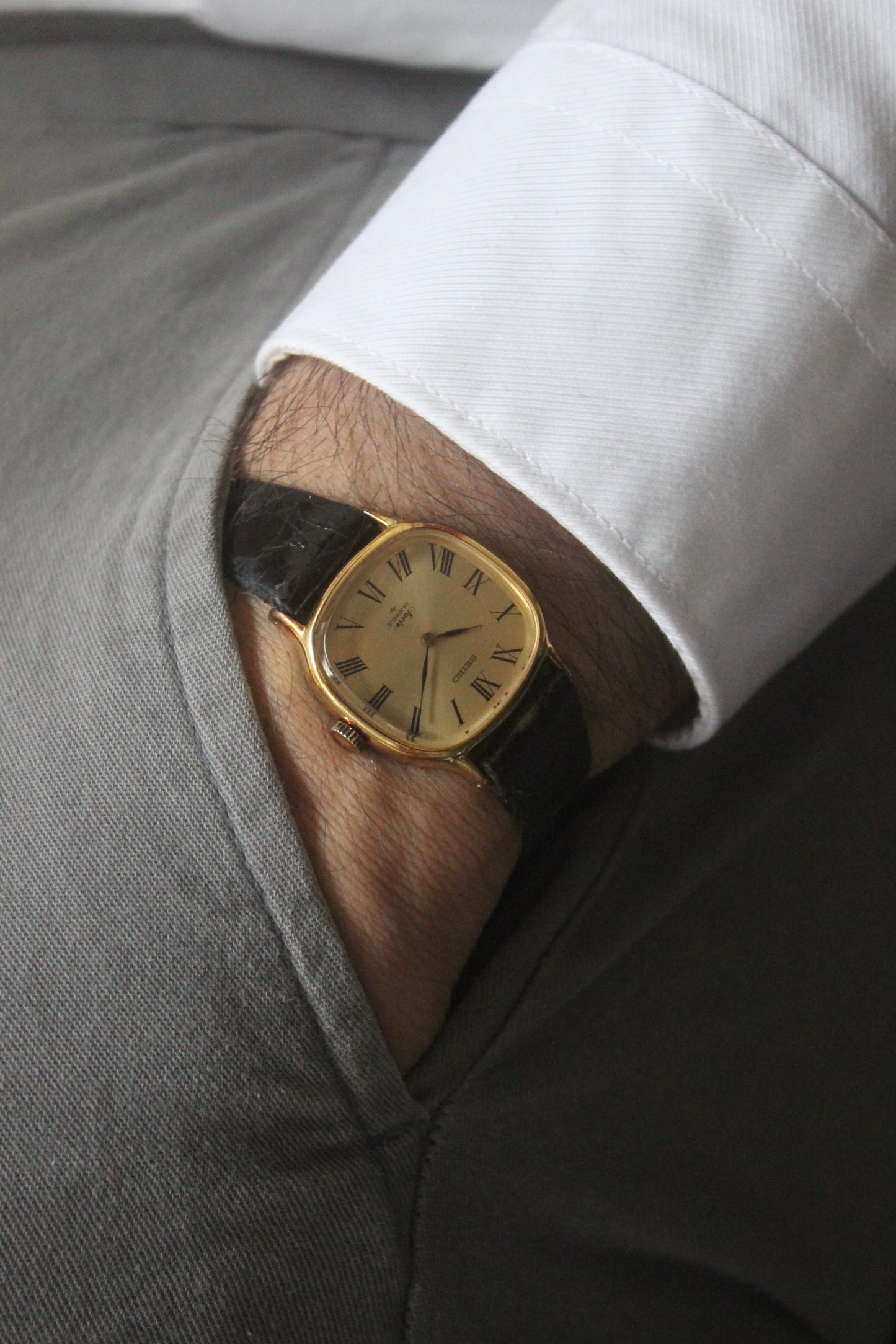 A close-up of the Seiko Socie Ref.
2220-3470, featuring a cushion-shaped gold-filled case, a champagne dial with black Roman numeral markers, and sleek black hands. Paired with a black leather strap, this vintage timepiece exudes elegance and timeless style.