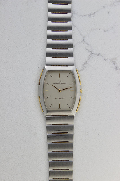 Front View of Universal Genève White Shadow Ref. 617-020
A close-up of the Universal Genève White Shadow Ref. 617-020, featuring a sleek tonneau-shaped stainless steel case with gold accents, a clean white dial, and minimalist stick hands and indices. Paired with an integrated stainless steel bracelet for timeless elegance.